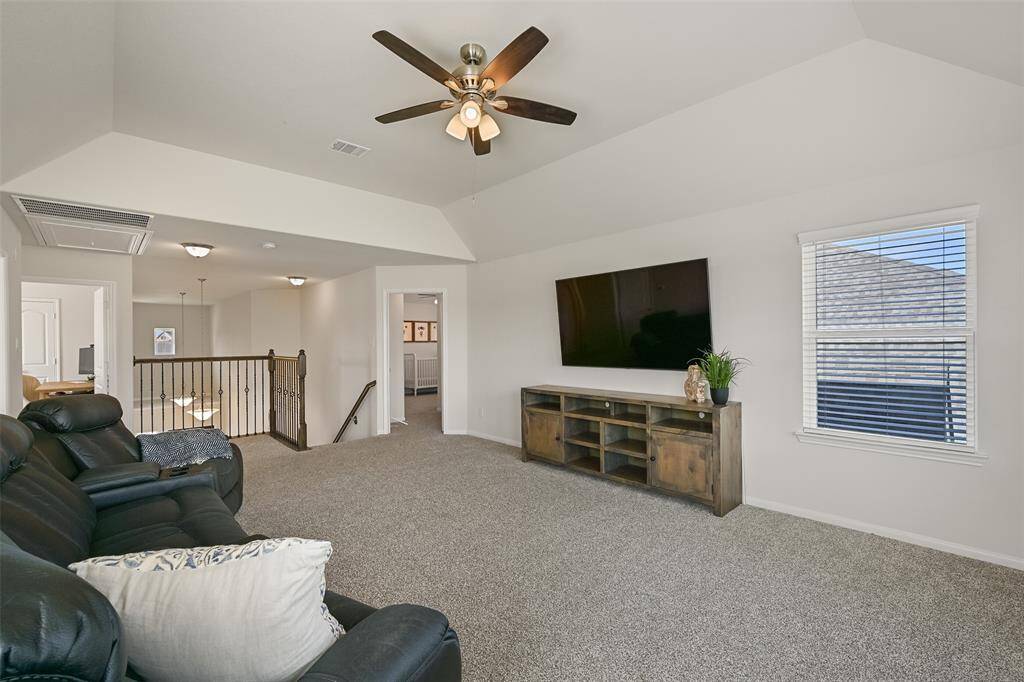 Head up the staircase from the foyer to this second-floor game room that's perfect for a family movie night! This space boasts an elevated gambrel ceiling with a lighted ceiling fan, plush carpet underfoot, and a wall of rear-facing windows with 2-inch blinds.