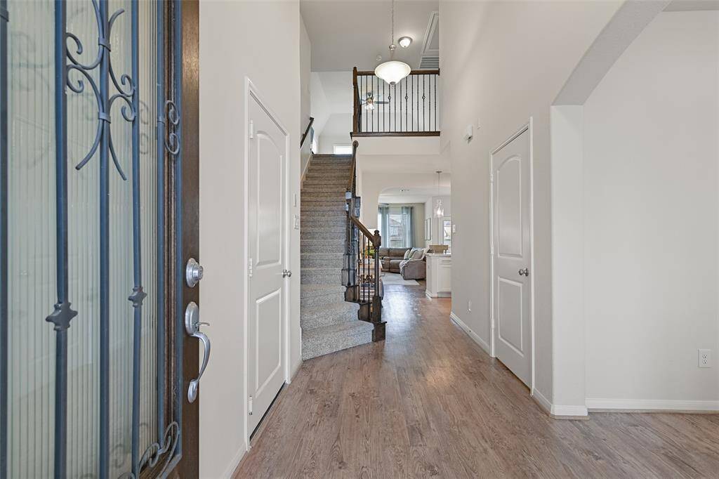 A solid mahogany and pleated glass door with wrought iron detailing opens from the covered front porch into this light & bright design with 2,602 square feet of beautifully appointed space with luxury vinyl plank floors and neutral paint throughout.