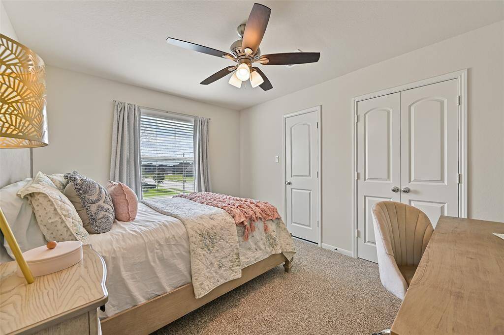 The fourth and final bedroom offers a modern-style lighted ceiling fan, front-facing window shaded by 2-inch blinds, plush carpet underfoot, a double door closet, and convenient walk-in access to the decked attic with an energy-saving tech shield barrier.