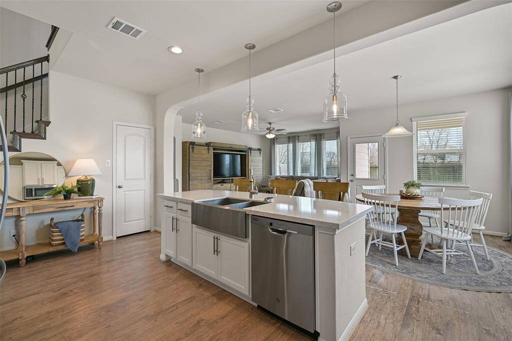 A glance from the kitchen towards the eat-in breakfast room and family room highlights the open concept functionality of this floorplan that's great for entertaining. Also note the door on the left that accesses a roomy storage closet or bonus pantry beneath the staircase.