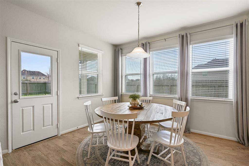 Enjoy your morning coffee or a casual family meal in this eat-in breakfast room that's bathed in natural lights streaming in from windows that encircle the space. Also note the continued luxury vinyl plank floors, pendant lighting, and half-glass panel back door.