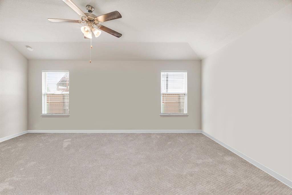 Here’s another view of the spacious primary bedroom, showcasing its expansive layout and abundant natural light. Two large windows provide a bright and airy atmosphere while maintaining privacy with views of the fenced backyard. Soft, neutral-toned carpeting adds warmth underfoot, and the ceiling fan ensures year-round comfort. With ample room for a king-sized bed and a full suite of furniture, this peaceful retreat is ready to become your personal haven.