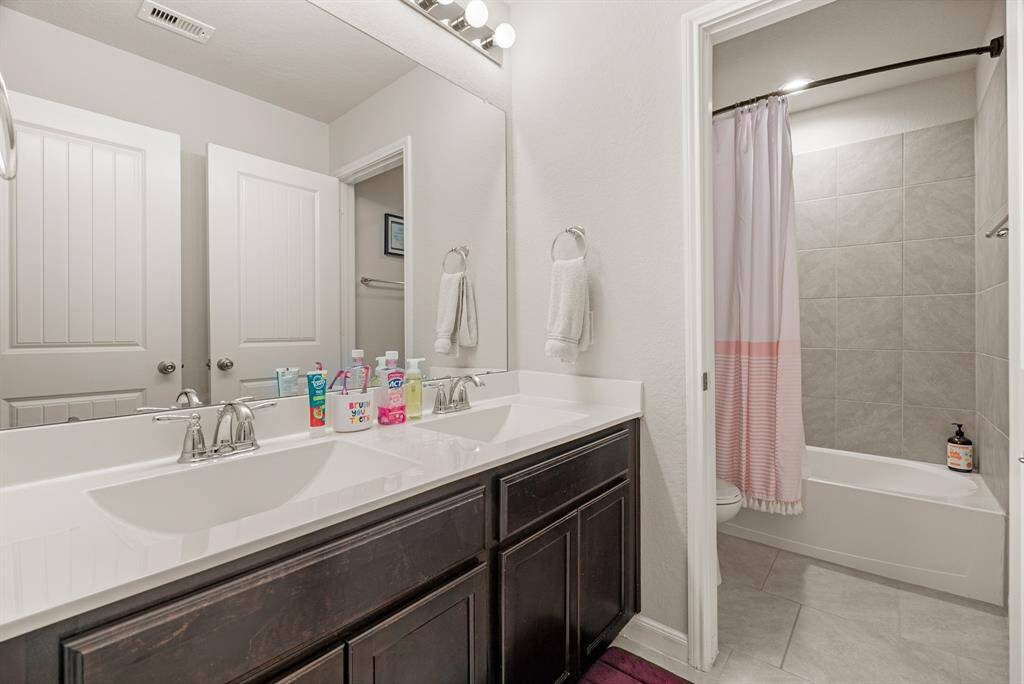 This secondary bathroom offers double sinks and a private toilet and bathtub area for enhanced functionality and privacy.