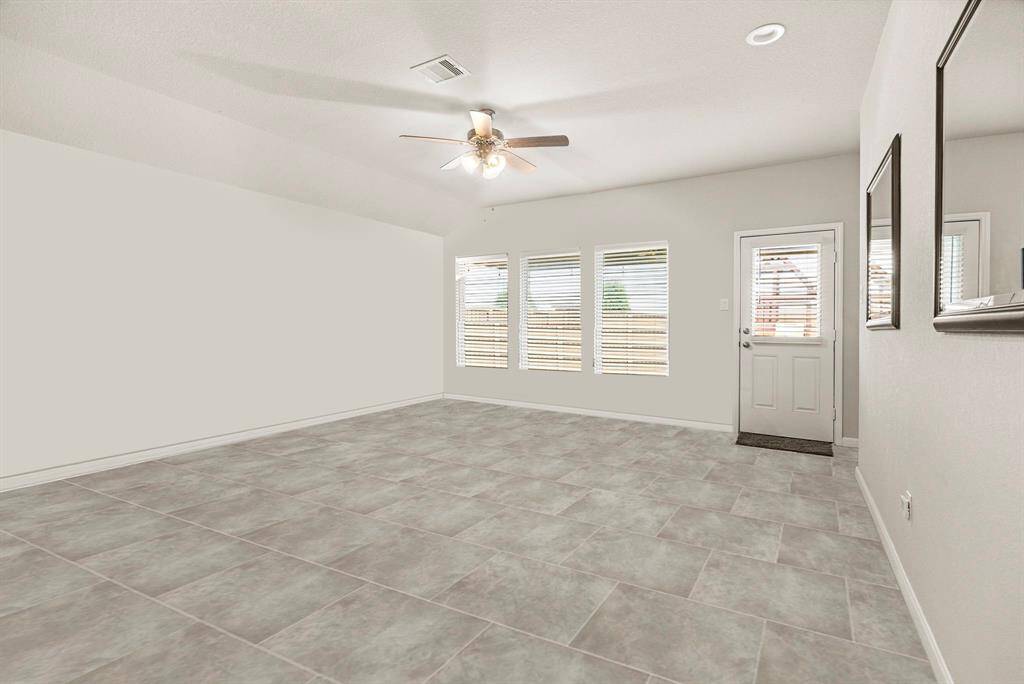Step into this spacious and light-filled living room, designed for both comfort and style. Featuring sleek tile flooring, a neutral color palette, this versatile space offers the perfect canvas for your personal touch. A wall of windows fills the room with natural light and provides a clear view of the backyard, while the adjacent door offers easy access to the patio—ideal for indoor-outdoor living. Whether you’re hosting guests or enjoying a quiet evening at home, this room is ready to accommodate.