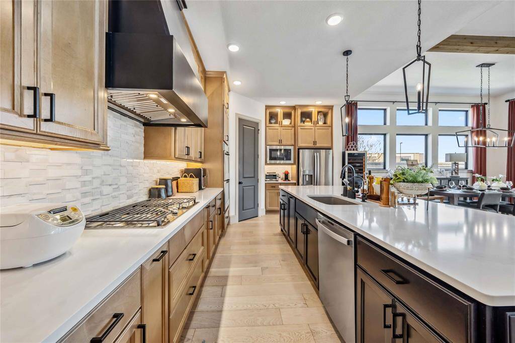 Enjoy a modern cooking experience with a gas cooktop, designer tile backsplash & built-in appliances—all framed by dual-tone cabinetry and under-cabinet lighting.
