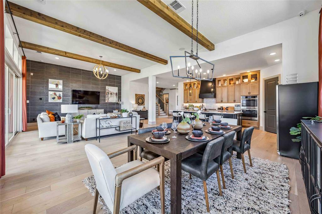 This view captures the seamless flow between the dining area, living room & chef-inspired kitchen, all under soaring ceilings with exposed beams.