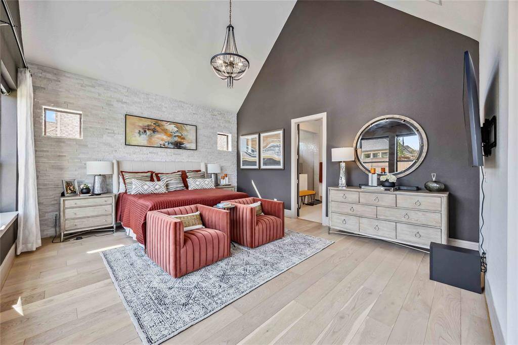 The spacious primary suite showcases a soaring vaulted ceiling, a dramatic accent wall, and rich natural light—creating a luxurious retreat just steps from the en-suite bath.