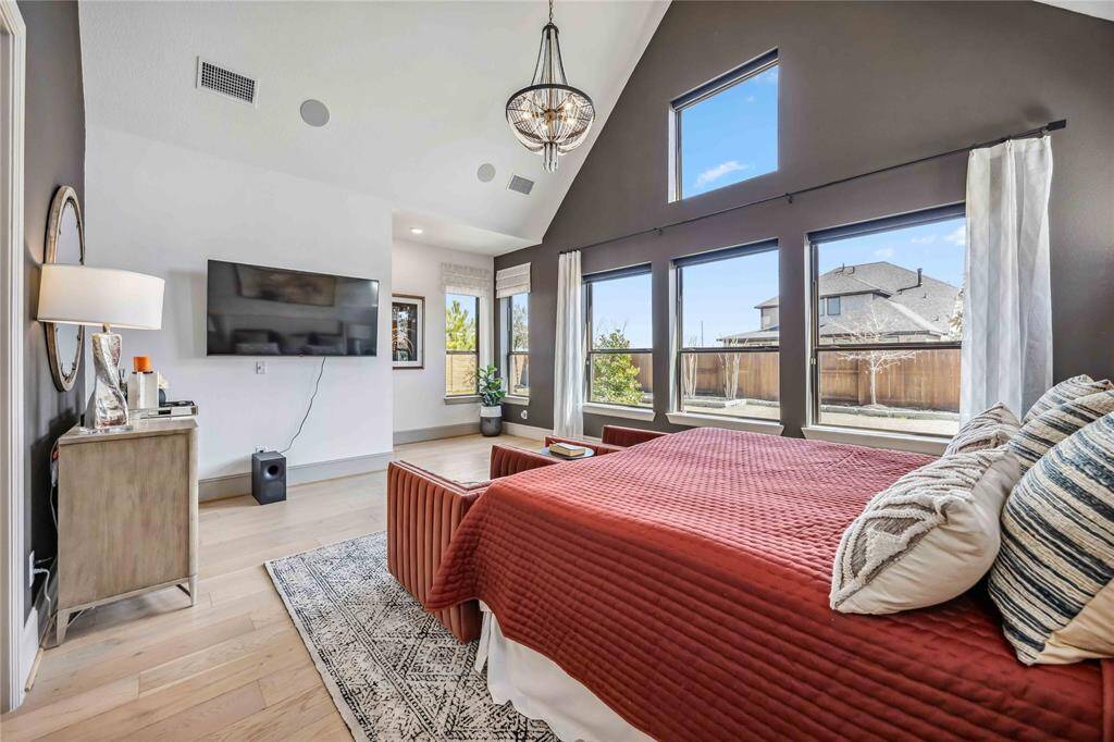 Wake up to serene backyard views through a full wall of windows that fill the room with natural light and highlight the tall, vaulted ceilings.