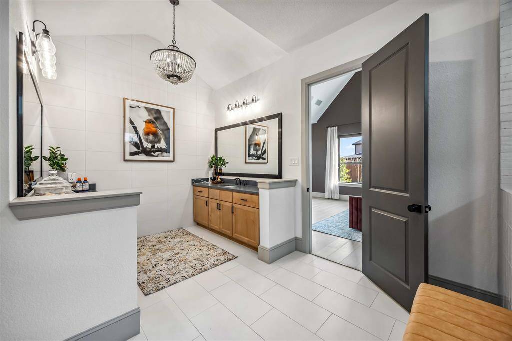 The primary bathroom features a spacious dual-sink vanity with stylish lighting, black countertops, and a modern tile backdrop for a clean, polished look.