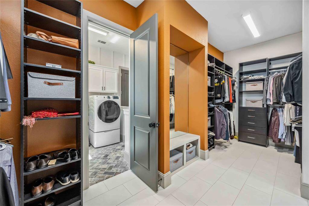 Custom shelving and stylish accent walls elevate this closet, which also connects directly to the laundry room for everyday ease.
