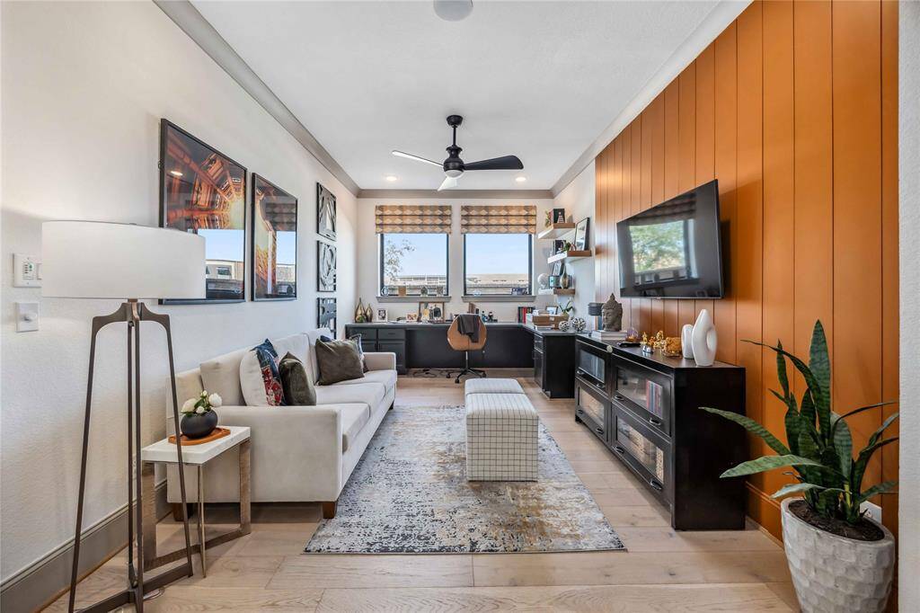 This stylish home office features a bold wood-paneled accent wall, built-in desk & shelving, and abundant natural light—perfect for productivity and comfort.