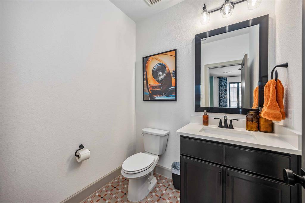 A convenient upstairs powder bath includes a sleek vanity, modern black-framed mirror, and patterned tile flooring.
