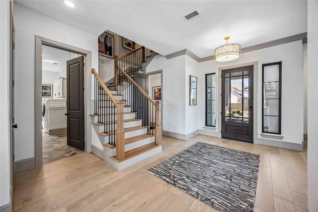 Welcoming entryway features elegant staircase and easy access to the laundry room and powder bath, combining function with beautiful design.