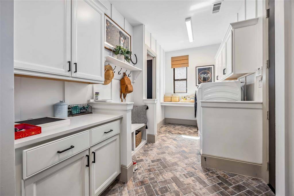 Expansive laundry room with built-in cabinetry, workstation, and a convenient drop zone with hooks and storage.