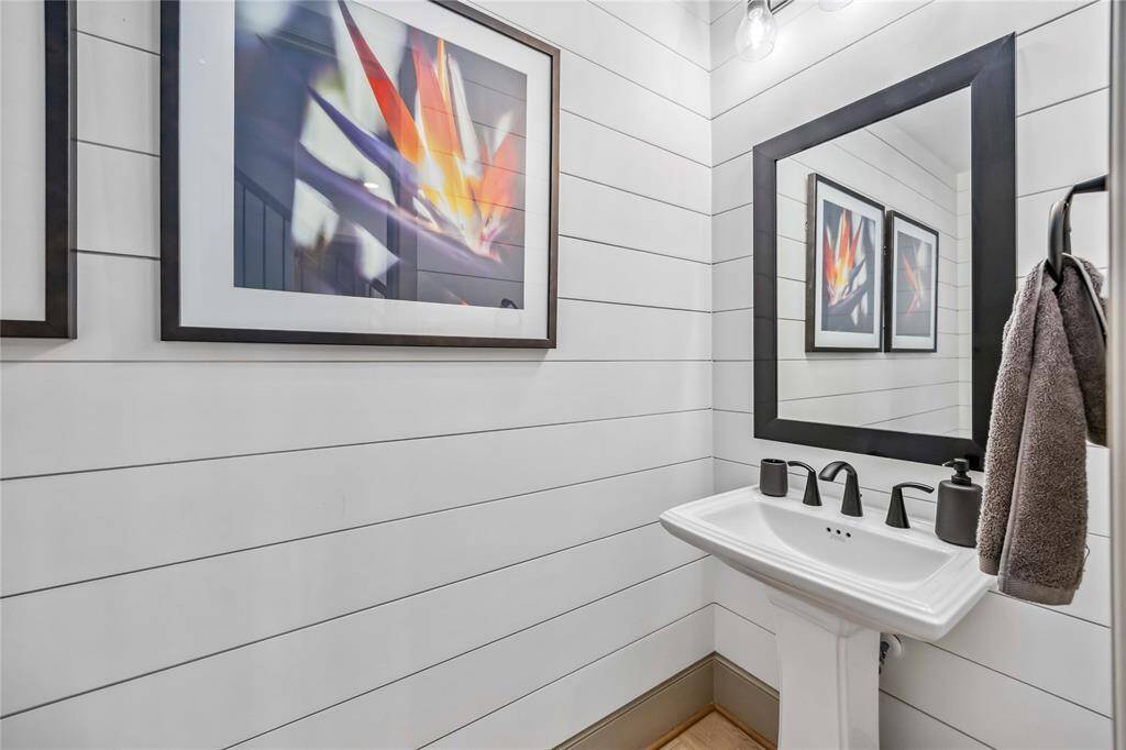 Chic powder bath featuring horizontal panel detailing, pedestal sink, and framed mirror—perfect for guests.