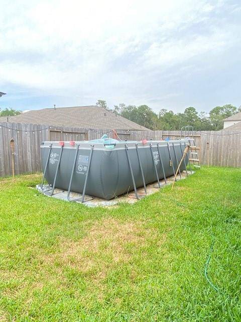 The backyard features a spacious grassy area and includes an above-ground pool with a ladder, set against a wooden privacy fence. Ideal for outdoor relaxation and entertainment.