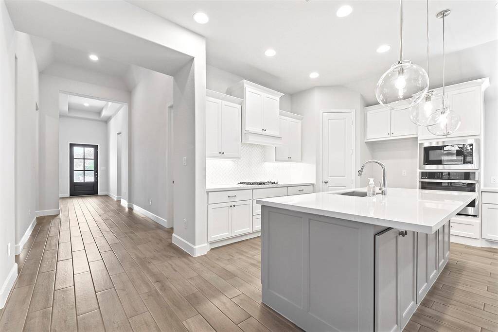 Stepping further into the home, you’ll notice the open layout. To the right, you'll find the guest hallway, which leads to two bedrooms and a full guest bathroom, followed by a large utility room. To the left, a mudroom provides access to the 2-car garage and leads to the junior suite bedroom with its own full bathroom.
