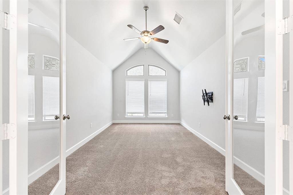 French doors lead into this beautifully framed flex space, featuring vaulted ceilings and a drop-down ceiling fan. It also includes a pre-wired home TV mount, perfect for an entertainment area or whatever suits your needs.