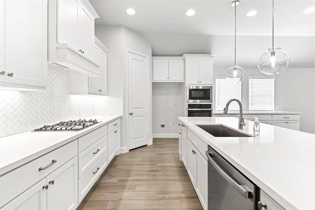 The kitchen offers all stainless steel appliances, elegant quartz countertops, and crisp white cabinetry with modern hardware. You'll love the farmhouse sink, pendant lighting over the island, and recessed lighting throughout. It also features a spacious walk-in pantry, wall oven, built-in microwave, and a gas cooktop—perfect for any home chef.