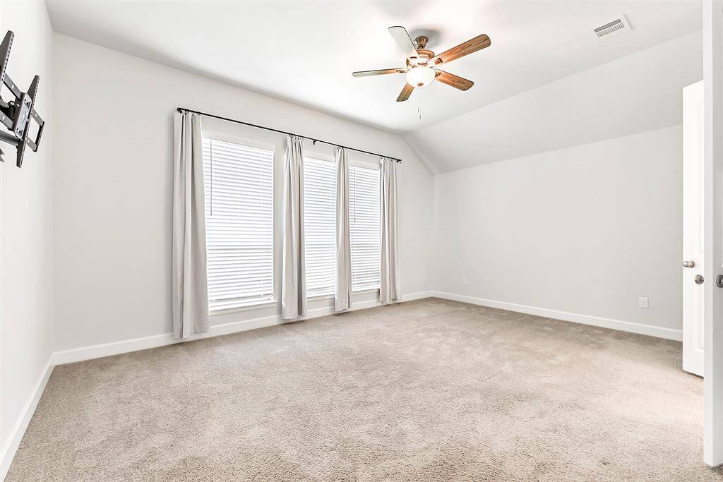 Welcome to the primary suite, featuring a wall of windows overlooking the backyard, plush carpeting, and a drop-down ceiling fan. French doors lead to a spa-like ensuite bathroom, creating a serene retreat within the home.