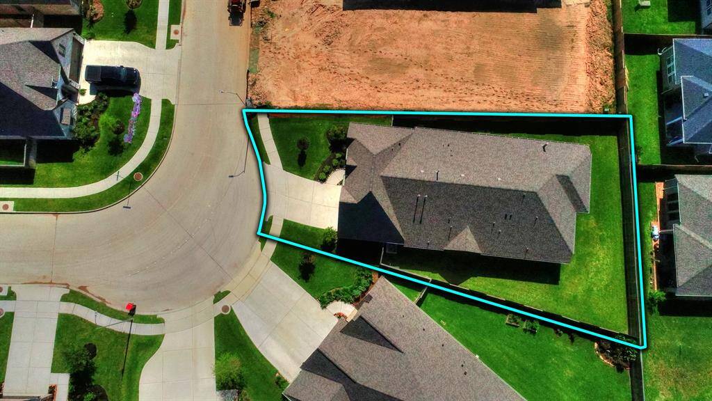 This bird's-eye view provides a comprehensive look at the roofline, emphasizing the home’s size and architectural features. It also highlights the low-traffic street and the large driveway, adding to the home's appeal and accessibility.
