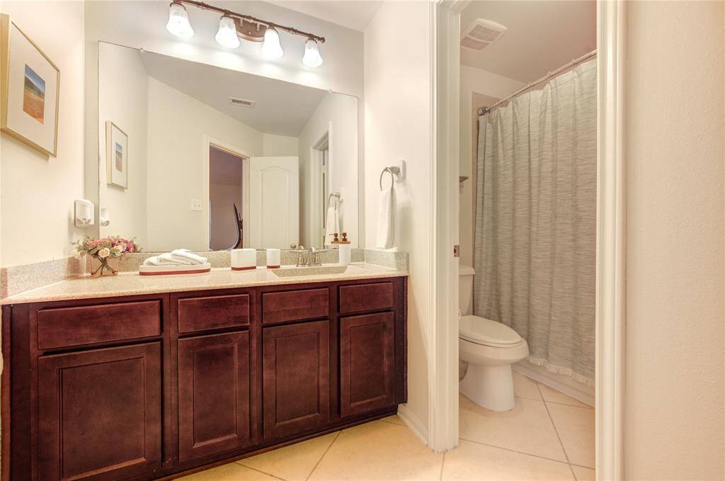 The secondary bathroom is thoughtfully designed with modern fixtures and a clean layout, offering convenience and comfort for family and guests alike. It features a spacious vanity, ample storage, and a well-appointed shower and tub combination