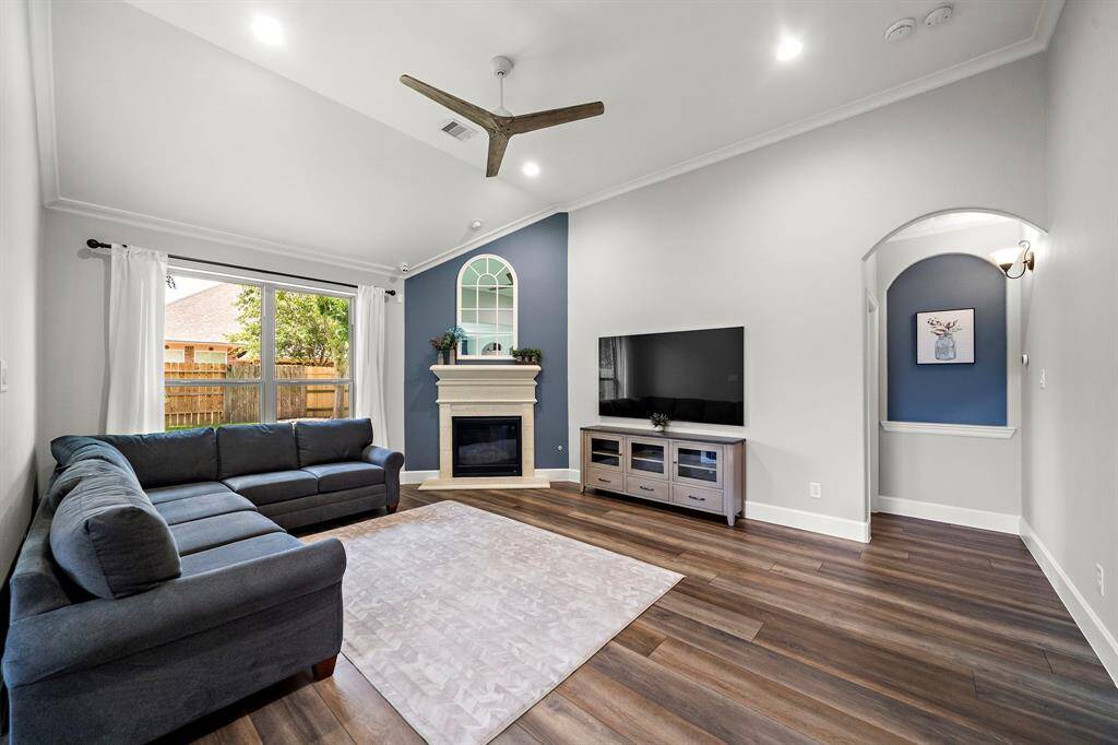 Cozy gas log fireplace framed by custom trim and a large picture window with backyard views.