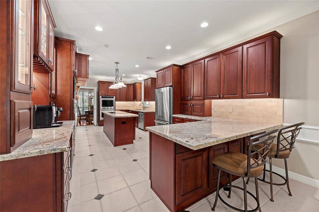 Alternate view of the kitchen showcasing abundant custom cherry cabinetry for storage and expansive countertop space—ideal for meal prep, entertaining, or everyday use.