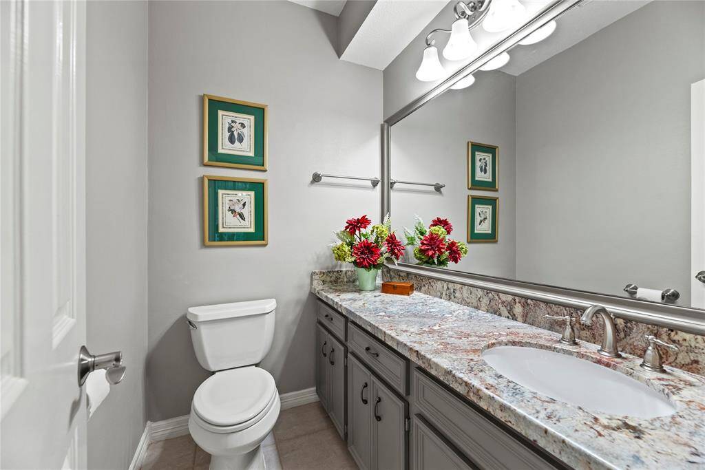 The half bathroom on the first floor is conveniently located between the laundry room and breakfast room. It features a granite countertop, large vanity/sink area, and a large mirror.