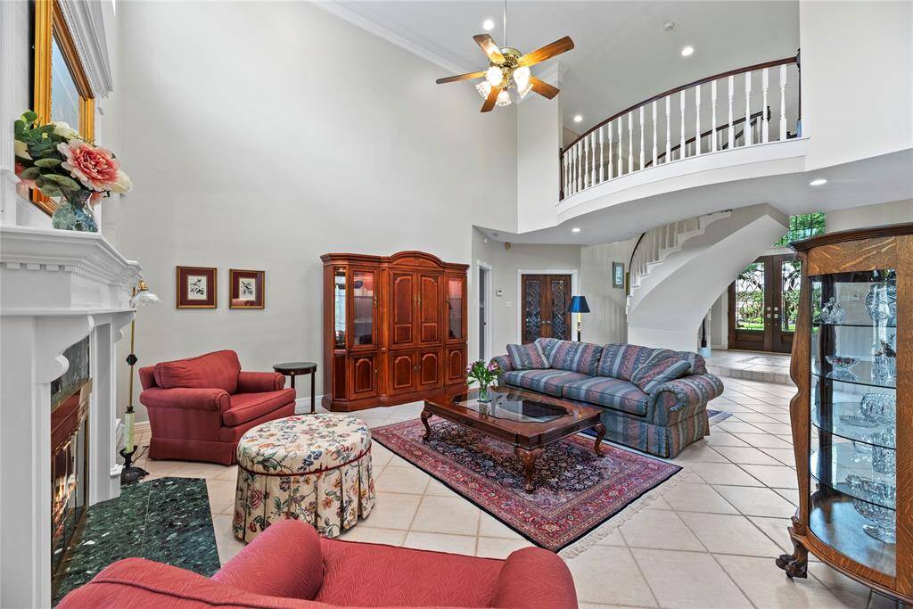The spacious family room boasts high ceilings, a fireplace, and windows that flood the space with natural light, creating an inviting and open atmosphere perfect for gathering and relaxation.