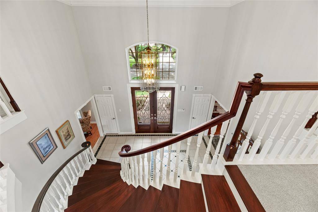 The front entryway features a grand curved staircase with new 3/4" oak treads, a chandelier, and natural light from a large arched window above the double front doors.