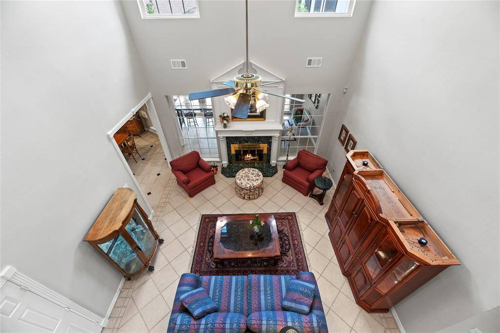 View of the spacious family room from the second floor, highlighting the soaring ceilings, large windows that flood the space with natural light, and the open-concept layout that connects seamlessly to the kitchen and living areas below.
