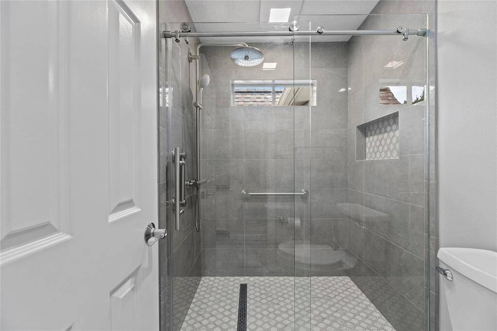 Bathroom #3 of the flex room and another bedroom with a spacious, glass slider door shower featuring sleek gray tiles and a rainfall showerhead.