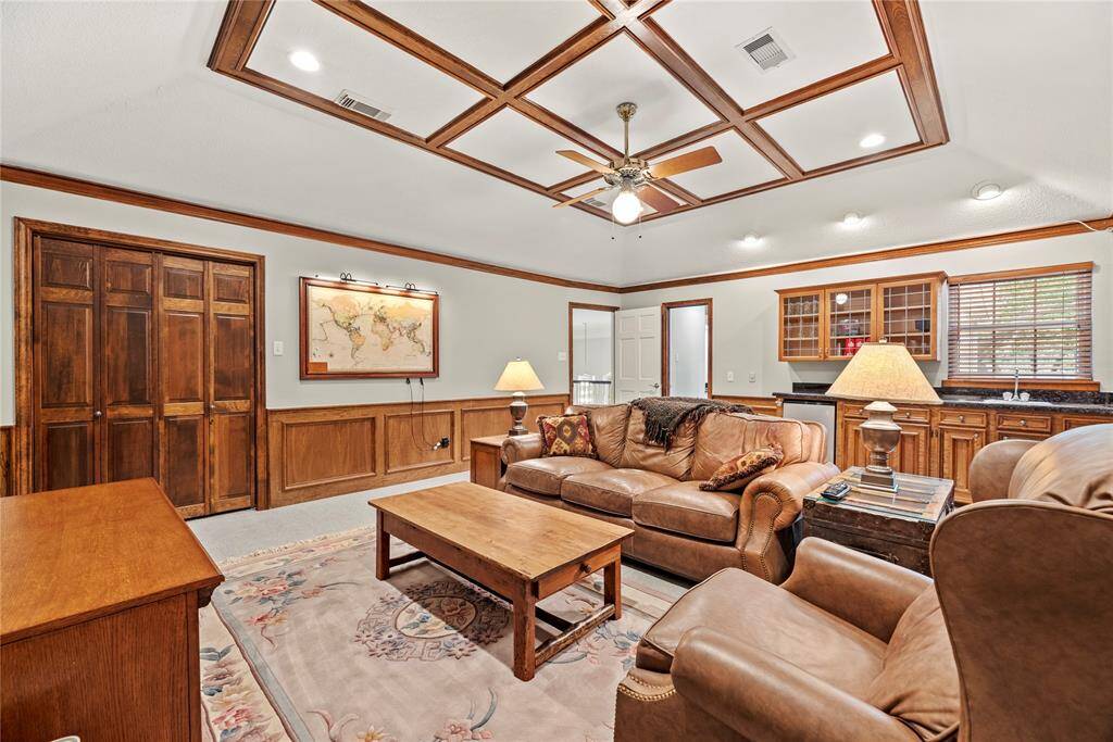 This spacious flex room measuring 15.3 x 19.9 features warm wood paneling, large storage closet and a decorative trimmed ceiling with a fan. A wet bar area adds functionality, while ample lighting create a bright, inviting space.