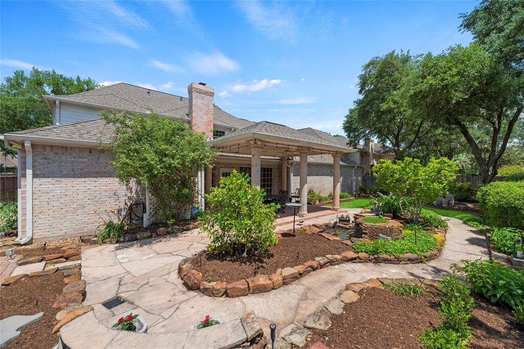 Alternate view of the backyard highlighting the stone pathway that winds through lush garden beds, creating a serene and picturesque outdoor space perfect for relaxation and outdoor enjoyment.