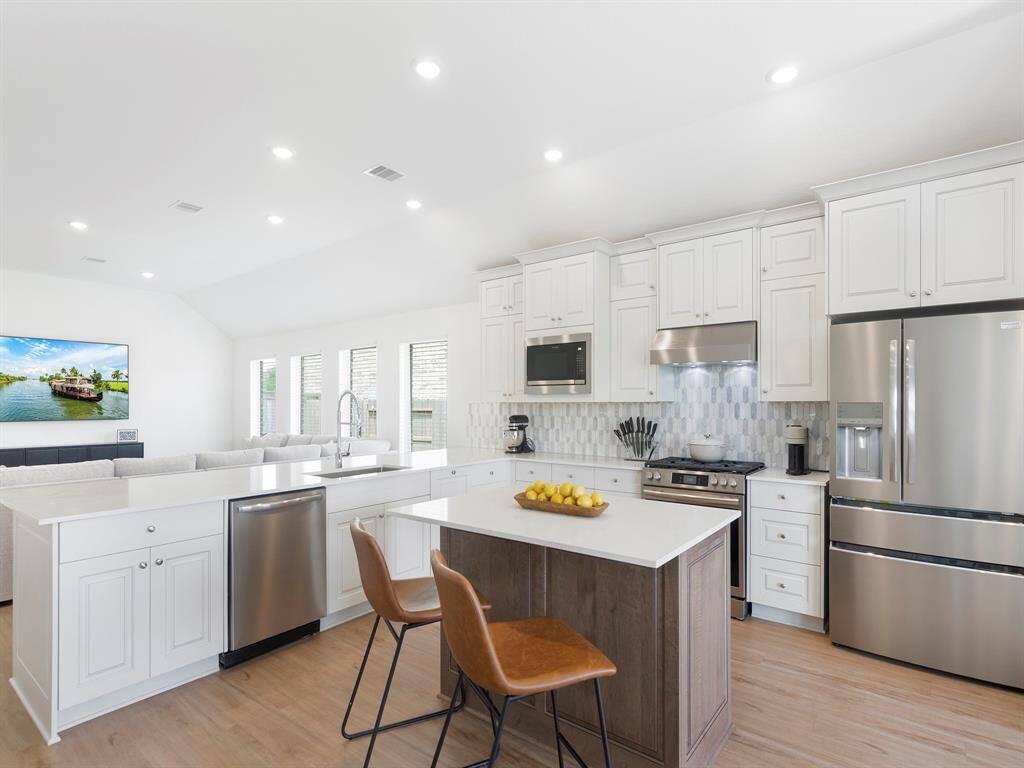 This cozy kitchen island seats two and offers extra prep space. This photo highlights the stainless-steel kitchen appliances, layout and stylish backsplash.