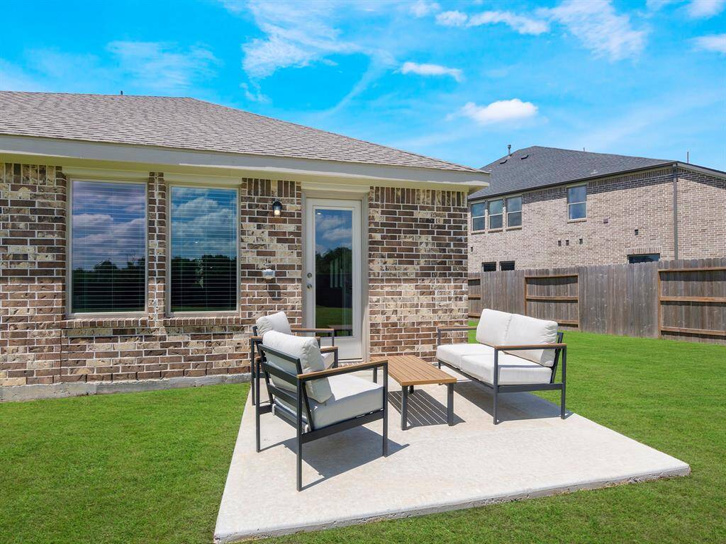 A modest concrete patio sits in the backyard, facing the home's beautiful brick exterior and offering a practical space for outdoor dining, grilling or relaxing.