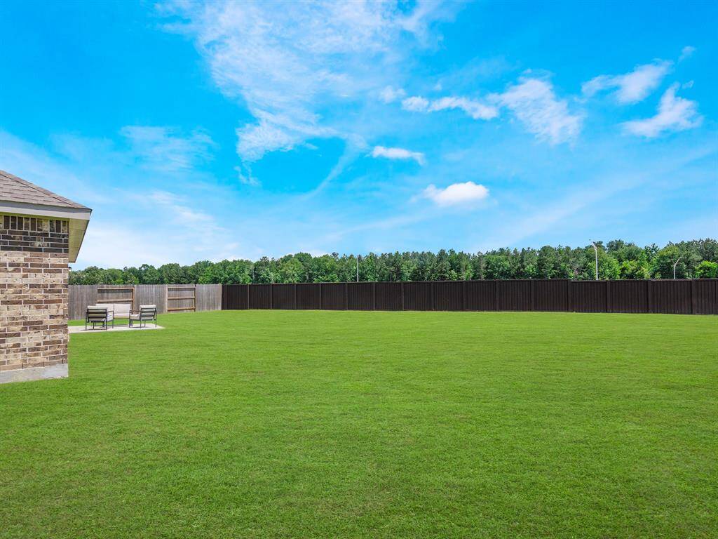 Well-maintained lawn, bordered by a tall fence for privacy.