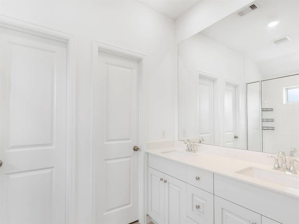 This all-white bathroom features polished nickel fixtures, double sink vanity and durable quartz countertop for a clean, timeless look.