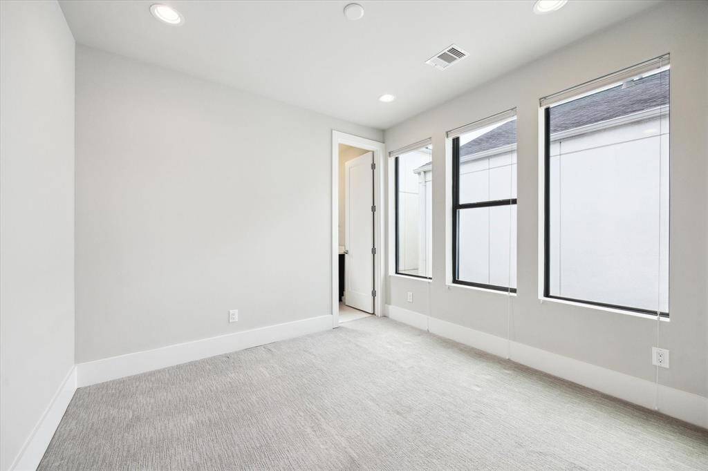 One of two spacious secondary bedrooms. This bedroom is located on the third floor and includes a full bathroom and large closet. All bedrooms boast custom top down bottom up blinds and a modern ceiling fan/light combo.