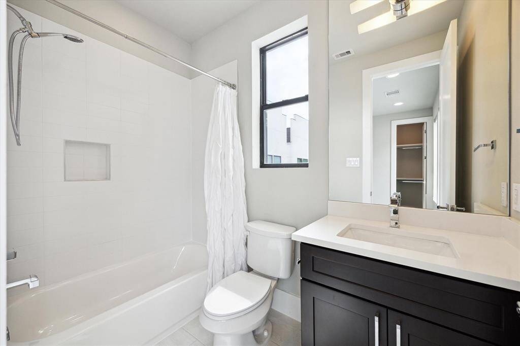 Gorgeous full bath ensuite to third floor secondary bedroom, featuring a shower/bath tub combo, gorgeous tiling, and quarts counters.