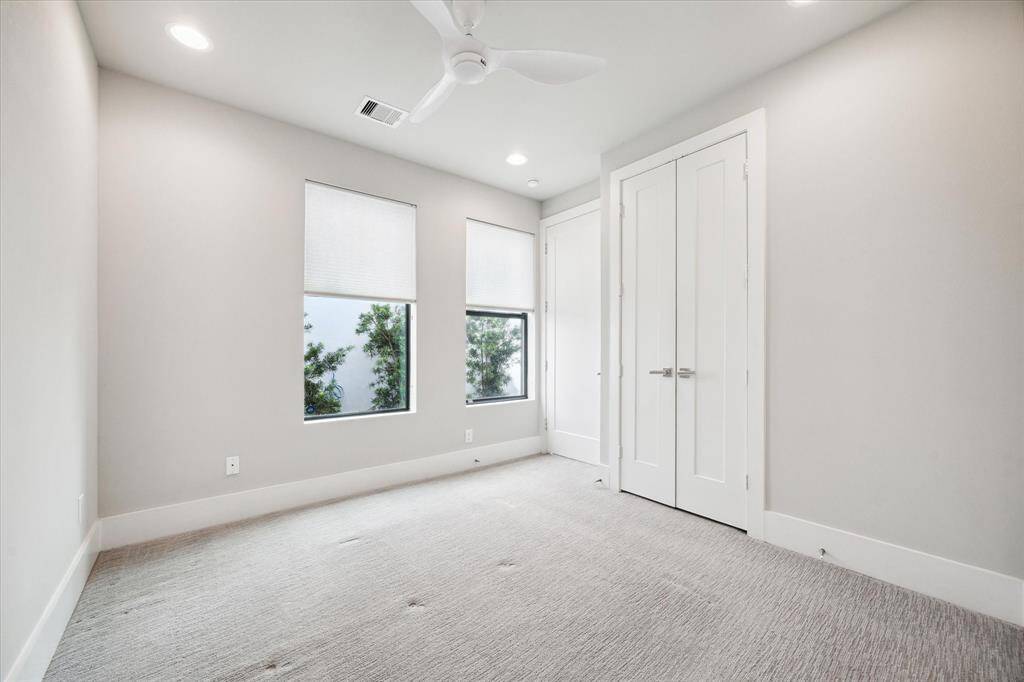 This spacious secondary bedroom located on the first floor and features custom blinds, modern ceiling fan/light combo, large closet with closet system, and a modern full bath. Perfect for a guest room or home office.