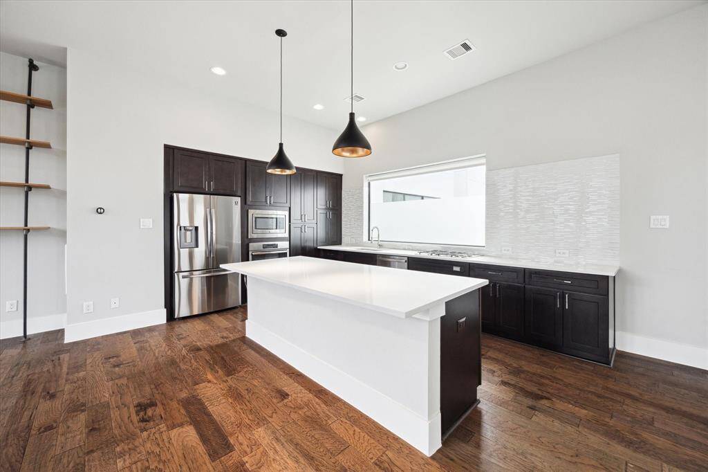 The stunning gourmet kitchen is complete with stainless steel appliances, a beautiful backsplash, and quartz counters. The large island has comfortably fits 4 barstools and features dimmable lighting under the ledge.