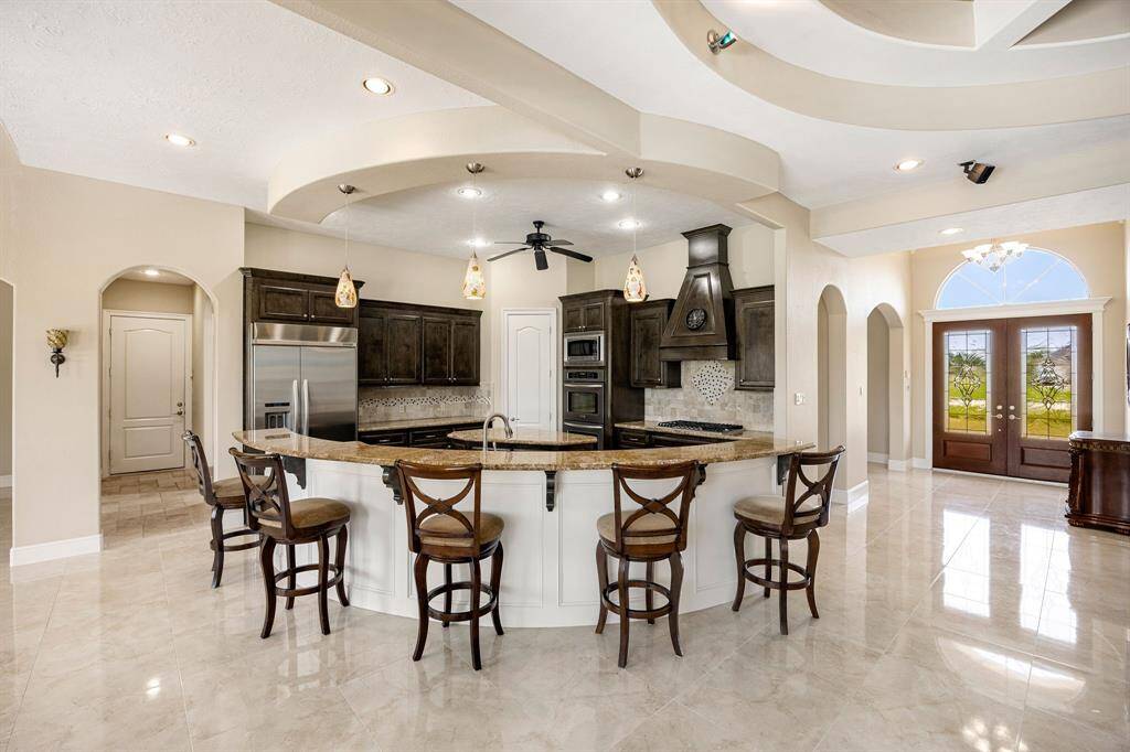Granite countertops define the inviting sit-up bar, perfectly accented by modern pendant lighting overhead.