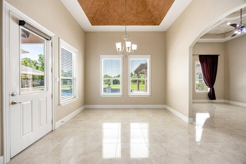 The breakfast nook features a detailed accent ceiling and opens directly to the formal den, creating a bright and connected living space.