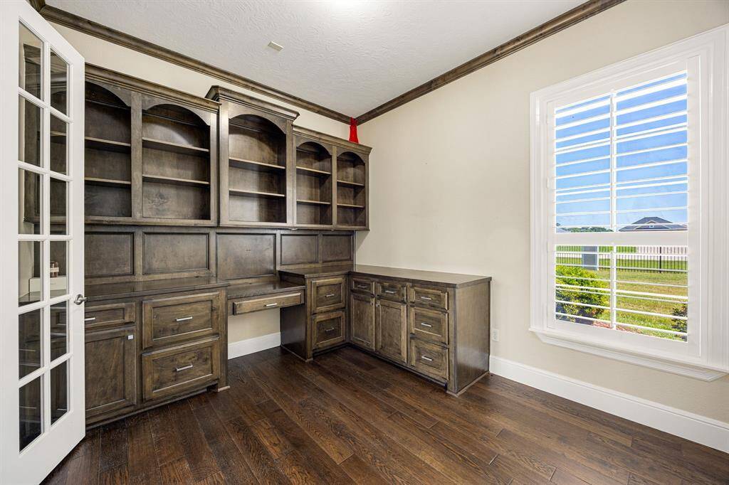 Study has custom built-in desk and shelving with a view of the front yard. French doors allow for privacy.