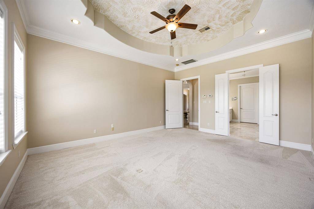 Another angle of the primary bedroom showcases the custom ceiling design and soothing neutral color palette.