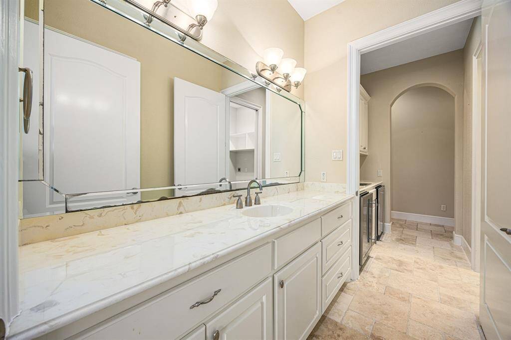 The secondary bedroom offers an en-suite with ample mirrored counter space, along with a convenient pathway to the garage and laundry area.