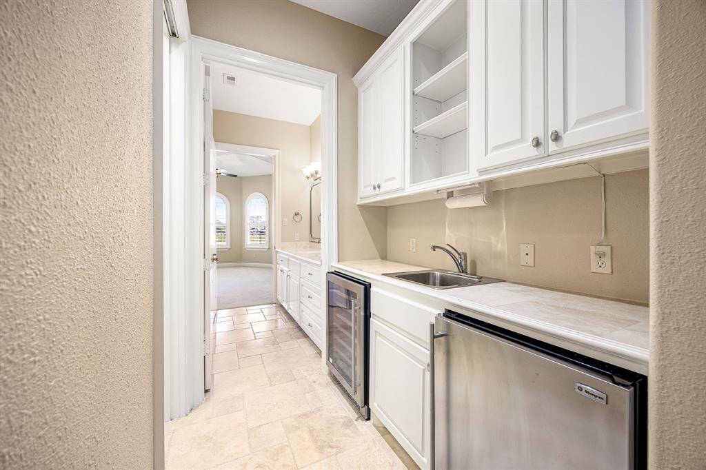 The bar area, conveniently located at the back of the kitchen, includes a wine cooler and additional beverage refrigerator—perfect for grabbing a drink before heading out to the pool!
