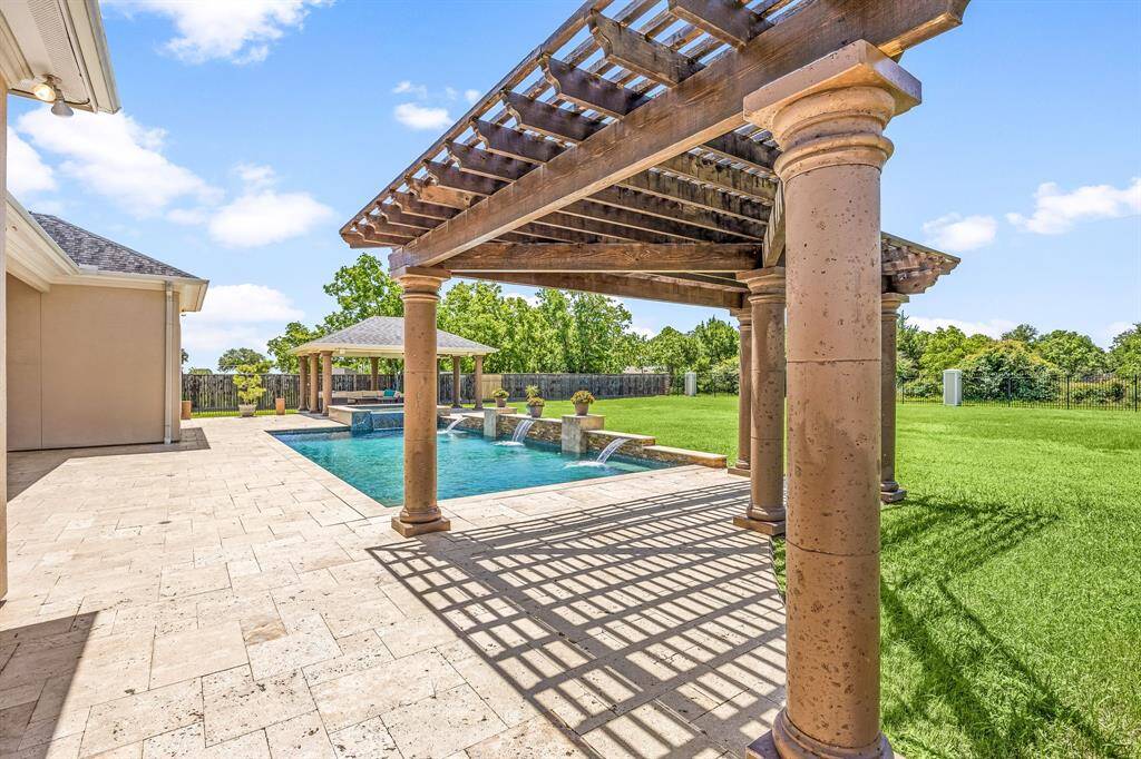 The charming pergola adds a decorative touch to the backyard while providing space for a cozy sitting area.